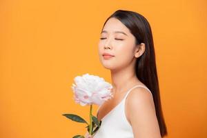 Young woman sniffing pink peony flower closed her eyes on yellow background photo