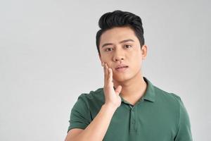 retrato de un joven apuesto asiático sin camisa revisando su rostro para el cuidado de la piel y conceptos de belleza, tiro de estudio aislado en fondo blanco foto