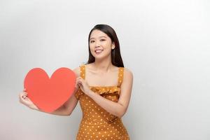 joven asiática sosteniendo una forma de corazón rojo foto