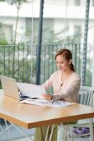 Charming businesswoman in glasses and striped shirt working with laptop computer while siting at home photo