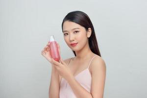 retrato de belleza de una atractiva joven asiática de pie, mostrando una botella foto