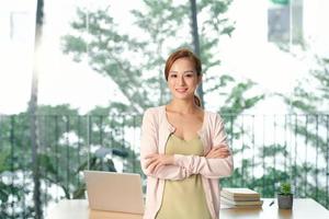 cheerful businesswoman standing with crossed arms in office photo