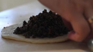 les mains des femmes ajoutent de la garniture de viande à un morceau de pâte. tarte maison fourrée. le chef fait de la pâte pour une tarte frite avec une garniture de viande bouillie. la ménagère remplit la pâte de viande et de légumes. video