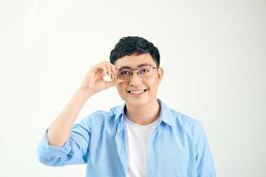 Closeup of friendly guy wearing eyeglasses. Young asian man adjusting glasses and staring at camera through lens. Vision and eye care concept photo