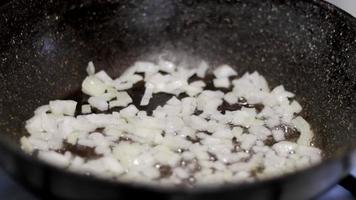 sofreír la cebolla picada en una sartén. freír las cebollas en un primer plano de la sartén. Beneficios y daños para la salud de las calorías de las cebollas fritas. video