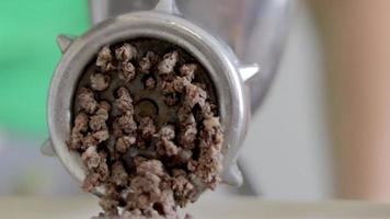 An incognito woman cooks meat in a home kitchen. Minced meat on a manual mechanical meat grinder. Fresh boiled meat is ground on an old metal meat grinder, close-up in the kitchen. video