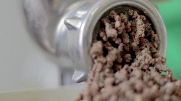 An incognito woman cooks meat in a home kitchen. Minced meat on a manual mechanical meat grinder. Fresh boiled meat is ground on an old metal meat grinder, close-up in the kitchen. video