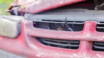 accidente en la calle, coche dañado tras una colisión en la ciudad. faros rotos como resultado de una colisión. coche rojo roto después de un accidente. faro, carrocería, capó y parachoques dañados. video