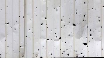 Close-up of a metal fence with bullet holes in the sunlight outdoors. The concept of the consequences of the war in Ukraine. Bullet holes in the fence of a residential building. panoramas. video