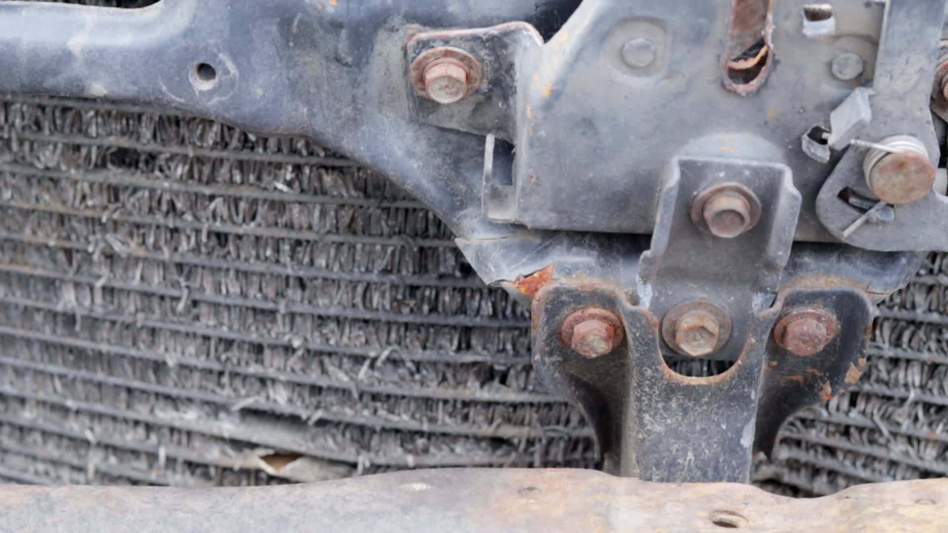 Hood lock and radiator grill of a blue car after an accident. Closeup