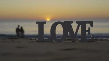 Letter Love on the sea sand tropical beach sunset background.