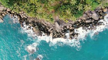 eau de mer vague turquoise roulant lent crash rochers littoral coucher de soleil paradis île de noix de coco.