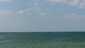 Lockdown shot of an airplane flying over the see. Profile of a commercial plane flying low over the sea about to land video