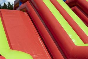 Inflatable slide of red color. Obstacle course in summer. Amusement park. photo