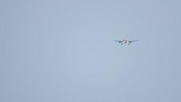 Long shot of an unrecognizable jet plane descending to land against a background of blue sky, haze video