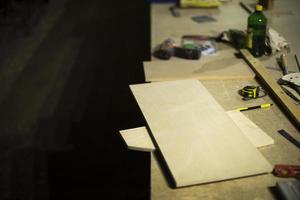 Table in wood workshop. Furniture assembler's workplace. Boards lying on table. photo