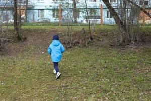 Child runs to fence. Kids got lost in street. Boy hurries home. photo