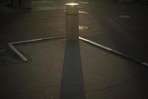 Urn in parking lot. Place to collect garbage on street. Shade from garbage on asphalt. photo