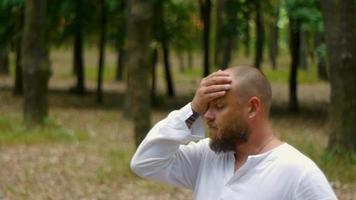 A man in a white shirt in a park with a beard reflects on the meaning of life video