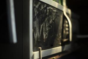 viejo horno microondas en polvo. equipamiento en cocina. horno microondas con cristal negro. foto