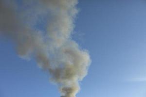 humo y cielo. el humo negro se eleva en el aire. foto