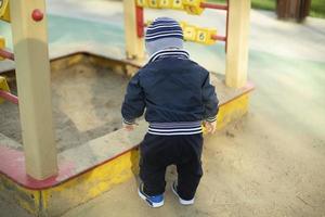 niño en caja de arena. niño en edad preescolar en el patio de recreo. foto