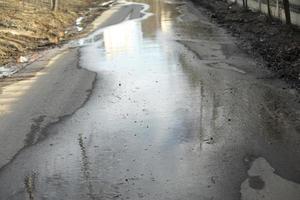 Puddle on asphalt. Wet road. Spilled water on pedestrian zone. photo