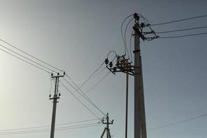 Poles with electrical wires. Silhouettes of communication racks. High voltage lines. Energy transfer. photo