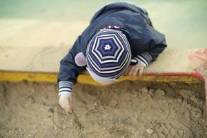 Child in sandbox. Preschooler on playground. photo