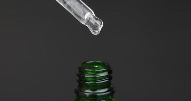 Pipette Cannabisöl-Extrakttropfen, der in Flasche auf dunklem Hintergrund tropft video
