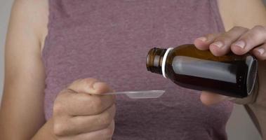 woman pouring cough syrup into a spoon to treat a cold video