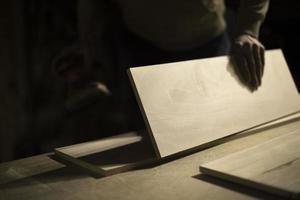 Carpenter holds tree. Worker chooses board. Details of carpentry workshop. photo