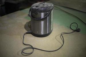 Old thermos. Electrical equipment on table. Boiler for warming water. photo