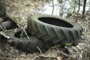 Old tires in landfill. Illegal release of waste into forest. Bad rubber lies on ground. photo