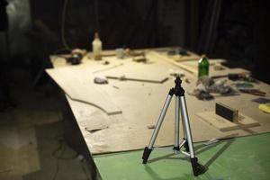 Tripod on table in carpentry workshop. Tool for shooting on camera. photo