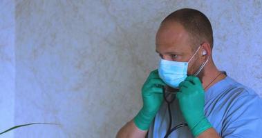 um homem com barba em traje de médico coloca uma máscara video