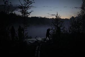 Man in fog on lake. Silhouette of man on shore. Outdoor recreation. photo