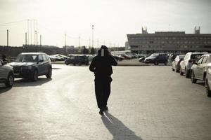 Man walks in parking lot. Man in town. Guy in square. photo