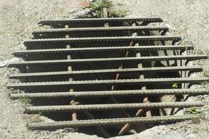 Manhole with grate. Steel grille on hole in asphalt. photo