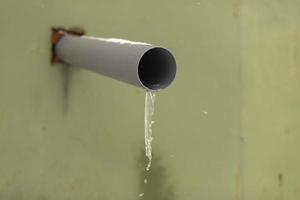 Pipe in wall. Plastic pipe comes out of wall to drain water. Water froze in sewers. photo