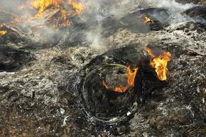 Burning wheels in landfill. Details of fire. Ashes and smoke. photo