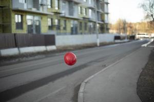Red balloon flies over road. Object is in air. Color contrast. photo