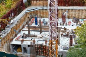 A fragment of a tower crane against the background of the construction site of the foundation of a new building. photo