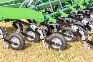 A fragment of a multi row knife harrow for field work against the background of the yellow stubble field. photo