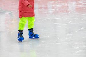 A teenager in bright clothes is skating in an ice stadium. photo