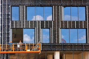 aislamiento de las paredes de un edificio en construcción e instalación de grandes ventanales en la fachada de un edificio residencial mediante un cabrestante y una plataforma móvil. foto