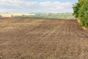 hileras suaves de tierra de campo arada en el contexto de un paisaje rural de verano. foto