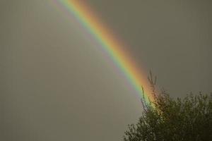 Rainbow in sky. Refraction of light. Weather after rain. Bright arc of different colors. photo