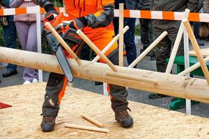 A worker deftly demonstrates his skill with a chainsaw at a lumberjack competition. photo