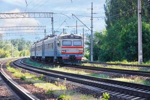 un viejo tren corre a lo largo del ferrocarril que sale de la ciudad en un día soleado de verano. foto